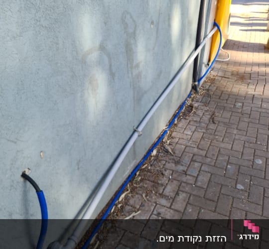 צינורות מים כחולים ואפורים מחוברים לקיר